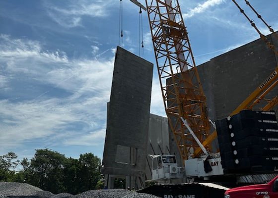 Crane lifting a concrete wall panel into place