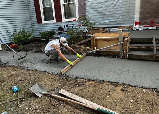 Worker screeding a freshly poured concrete walkway