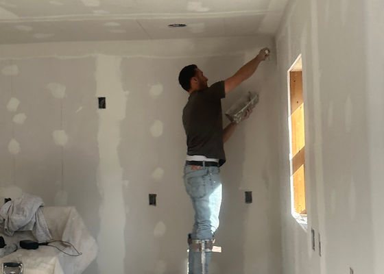 Worker taping and finishing new drywall