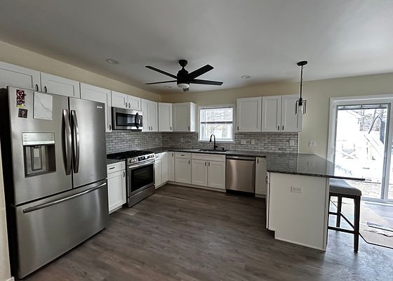 Kitchen with white shaker cabinets, stone counters, tile backsplash and stainless appliances