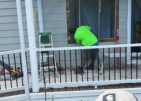 Worker framing a window opening on a covered porch